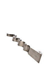 Adventsljusstake av Walter Andersson för Ystad Metall i krom. I ena änden återges en stiliserad knäböjande figur i bön med subtila art déco-influenser.