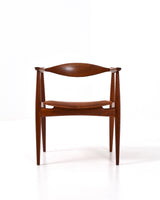 Karmstol av Hans J Wegner i massiv brunt teak. Sits klädd i brunt läder, med patina.