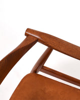 Karmstol av Hans J Wegner i massiv brunt teak. Sits klädd i brunt läder, med patina.