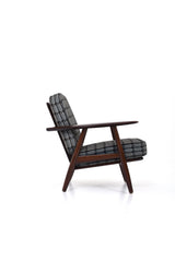 Fåtölj i brunt trä med dynor i rutigt tyg. Fåtölj GE-240 "Cigarren" av Hans J. Wegner för Getama