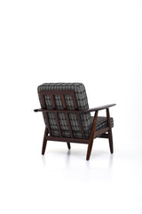Fåtölj i brunt trä med dynor i rutigt tyg. Fåtölj GE-240 "Cigarren" av Hans J. Wegner för Getama