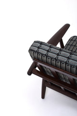 Fåtölj i brunt trä med dynor i rutigt tyg. Fåtölj GE-240 "Cigarren" av Hans J. Wegner för Getama