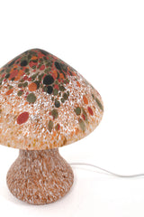Bordslampa i forma av en svamp i glas. Färgerna brunt, orange, vitt och mörkgrönt.