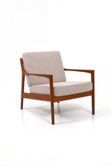 Fåtölj i teak och dynor klädda i beige ulltyg. Modellen heter USA 75 och designad av Folke Ohlsson för Dux.