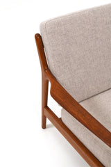 Fåtölj i teak och dynor klädda i beige ulltyg. Modellen heter USA 75 och designad av Folke Ohlsson för Dux.