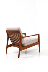 Fåtölj i teak och dynor klädda i beige ulltyg. Modellen heter USA 75 och designad av Folke Ohlsson för Dux.