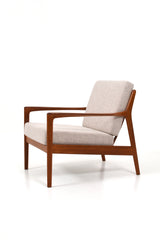 Fåtölj i teak och dynor klädda i beige ulltyg. Modellen heter USA 75 och designad av Folke Ohlsson för Dux.