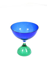 Blå glasskål på fot som är i grönt glas.