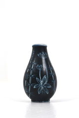 Keramikvas i mörkblå botten med vit dekor föreställande växter.