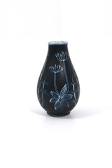 Keramikvas i mörkblå botten med vit dekor föreställande växter.